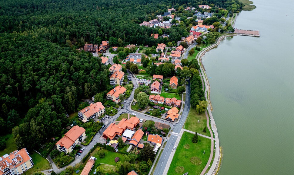 Juodkrantė iš oro: pušynas, raudonstogės sodybos ir marių krantinė.